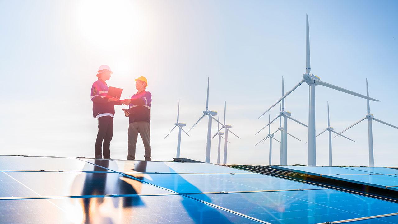 Two people shake hands at a wind and solar farm